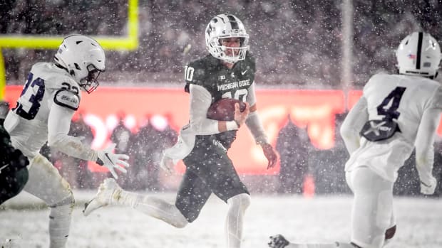 EAST LANSING, MICHIGAN - NOVEMBER 27: Payton Thorne #10 of the Michigan State Spartans runs the ball against Curtis Jacobs #23 and Kalen King #4 of the Penn State Nittany Lions during the fourth quarter at Spartan Stadium on November 27, 2021 in East Lansing, Michigan. (Photo by Nic Antaya/Getty Images)
